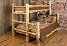 a wooden bunk bed sitting on top of a hard wood floor next to a stone wall