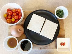 some food is on a black plate with bowls of vegetables and sauces next to it