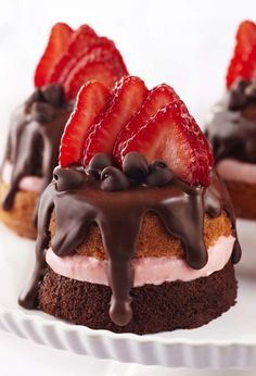 three desserts with strawberries and chocolate drizzled on the top one