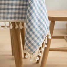 a blue and white checkered table cloth with tassels on wooden stools