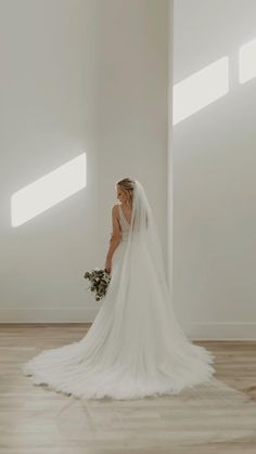 a woman in a wedding dress is standing on the floor with her back to the camera