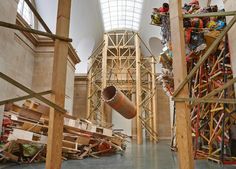 the inside of a building with scaffolding and workers working on wooden beams in it