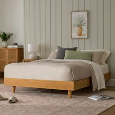 a bed sitting on top of a wooden floor next to a dresser and lamp in a bedroom