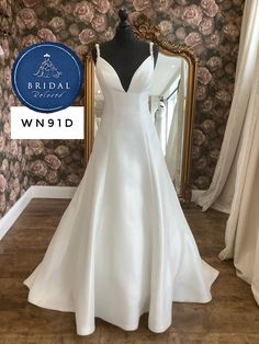 a white wedding dress on display in front of a mirror