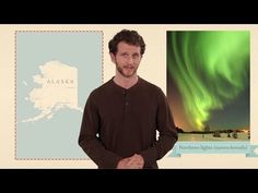 a man standing in front of a green and blue aurora sign with the northern lights behind him