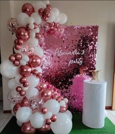 a pink and white balloon arch next to a roll of toilet paper