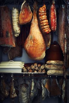 various meats hanging from hooks in a kitchen