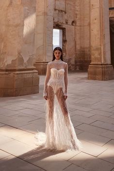 a woman standing in front of an old building wearing a dress with feathers on it