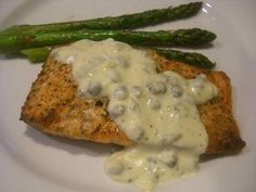 a white plate topped with meat covered in gravy and asparagus