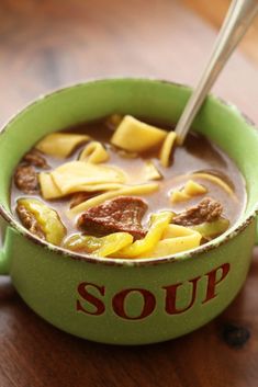 a green bowl filled with soup on top of a wooden table