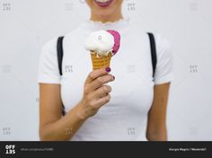 a woman holding an ice cream cone with pink sprinkles