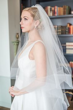 a woman wearing a wedding veil in front of bookshelves