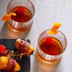 old fashioned cocktails with orange peel garnishes and cherries on the rocks