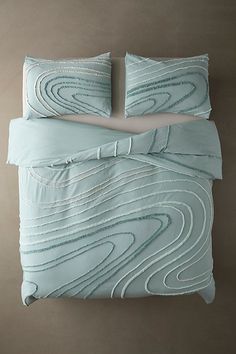 a bed with two pillows on top of it next to a pillow case and blanket