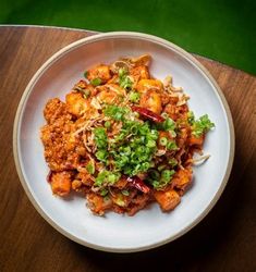 a white plate topped with food on top of a wooden table next to a green wall