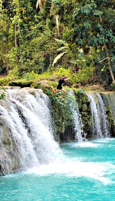 a man jumping into the water from a waterfall