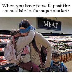 a woman with blindfolded head and child walking through a grocery store filled with food