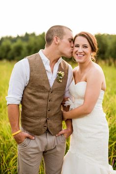 a bride and groom kissing in a field