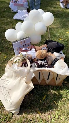 a teddy bear sitting on top of a wooden bench next to white balloons and other items