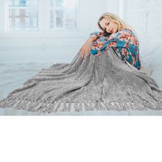 a woman laying on top of a bed covered in a blanket