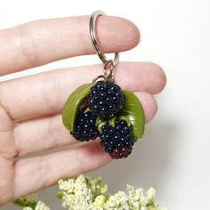 a hand holding a keychain with berries on it