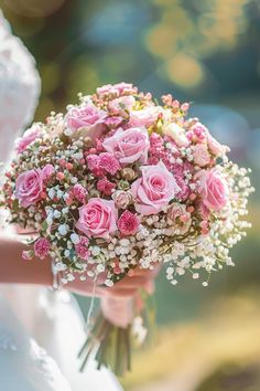 a bridal holding a bouquet of pink roses and baby's breath