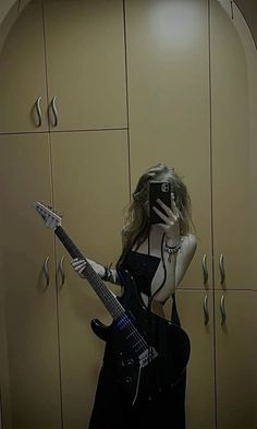 a woman is taking a selfie with her cell phone while holding an electric guitar