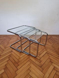 a glass and metal coffee table sitting on top of a hard wood floor next to a wall