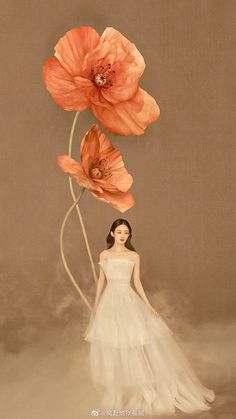 a woman in a white dress standing next to two orange flowers