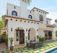 a large white house with a pool in the front yard and patio furniture on the side