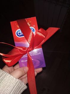 someone is holding up a card with a red ribbon on it that has the letter d on it