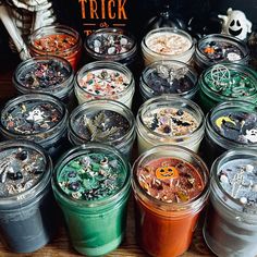 there are many different colored jars with halloween decorations in them and the words trick on top