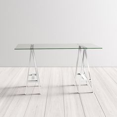 a glass table sitting on top of a hard wood floor next to a white wall