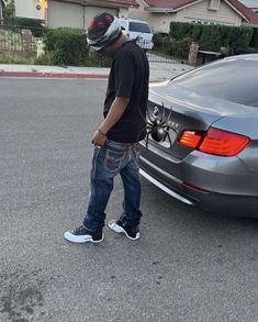 a man standing in front of a car with his foot on the ground next to it