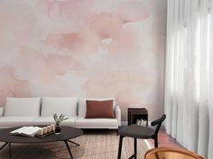 a living room with a couch, coffee table and chair in front of a pink painted wall