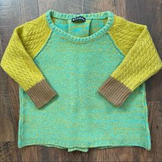 a green and yellow sweater sitting on top of a wooden floor