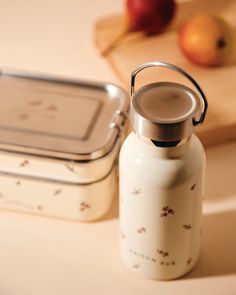 a white bottle sitting on top of a counter next to an apple