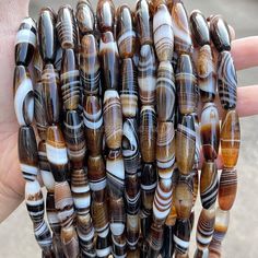 a hand holding several strands of brown and white glass beads in it's palm