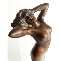 a bronze statue of a woman with her arms behind her head