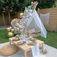 a table set up for a party with balloons, plates and napkins on it