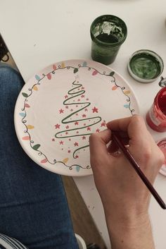 a person painting a christmas tree on a plate