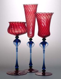 three red and blue glass goblets sitting next to each other on a table