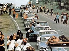 a group of people walking on the side of a road next to cars and trucks