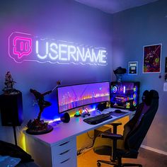 a desk with a computer, keyboard and mouse in front of a neon sign that reads username