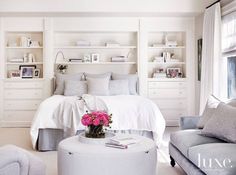 a bedroom with white furniture and pink flowers on the table in front of the bed