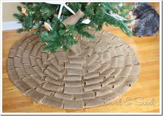 a christmas tree skirt made out of burlock and twine with a dog sitting next to it