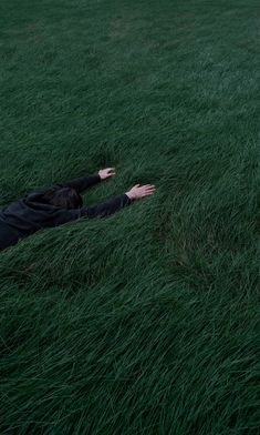 a person laying in the grass with their arms out