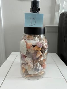 a jar filled with sea shells on top of a white counter