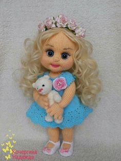 a doll with blonde hair holding a white teddy bear wearing a blue knitted dress