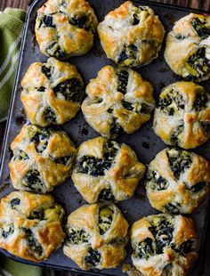 a baking tray filled with spinach and cheese muffins on top of a green towel